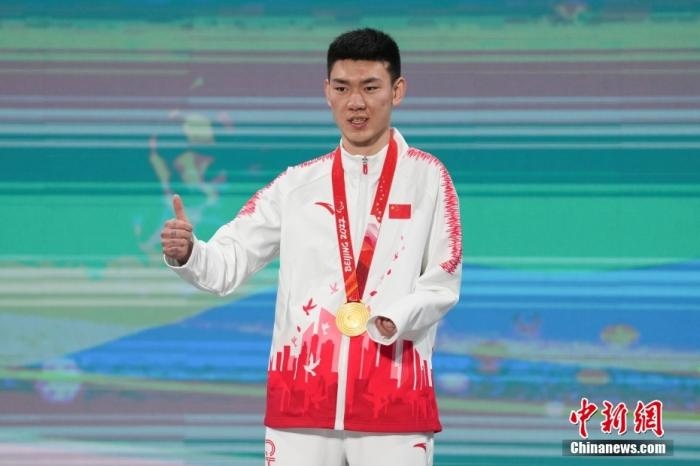 3月6日，梁景怡在延慶頒獎廣場領獎臺上豎起大拇指。當日，在國家高山滑雪中心舉行的北京2022年冬殘奧會殘奧高山滑雪男子超級大回轉—站姿決賽中，中國選手梁景怡奪得冠軍。 <a target='_blank' href='/'>中新社</a>記者 楊華峰 攝