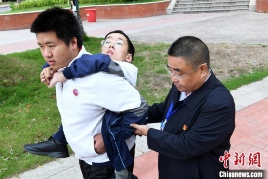 朱金祥背著鐘華強去教室上課的路上，也經(jīng)常碰到值班的校領(lǐng)導(dǎo)和老師前來搭把手。 卓忠偉 攝