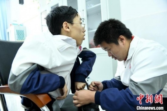 江西省南康中學(xué)北校區(qū)的高三學(xué)生朱金祥(右)正在給鐘華強(左)系好鞋帶。 卓忠偉 攝