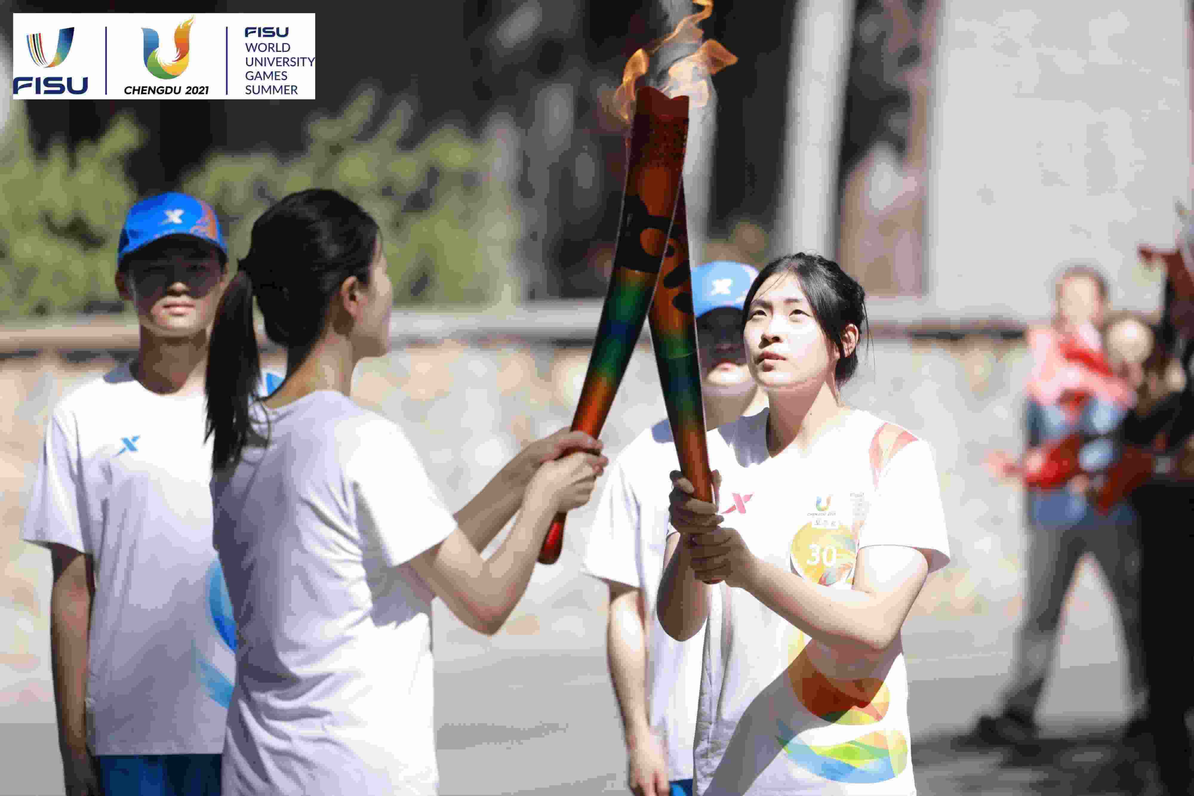 兩名大運會火炬手進(jìn)行火炬?zhèn)鬟f。 圖片來源：成都大運會執(zhí)委會供圖