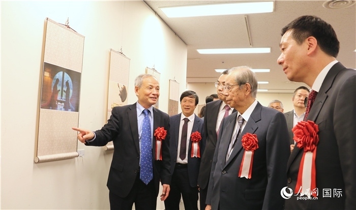 “湖州印象”攝影展主創(chuàng)、世界華人攝影協(xié)會(huì)副會(huì)長(zhǎng)馮學(xué)敏向吳江浩大使、福田康夫前首相等嘉賓介紹展出作品。（人民網(wǎng) 許可攝）