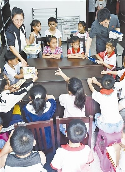  圖④：法院干警為留守兒童發(fā)放暑假讀物。