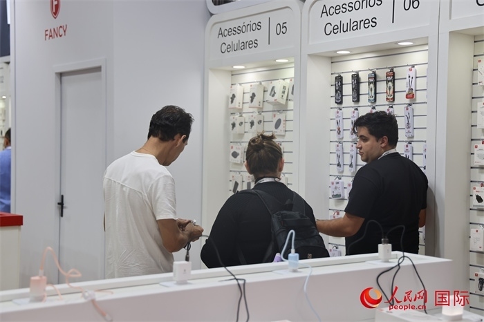 幾名參觀者在一個展臺前了解手機(jī)配件。（人民網(wǎng)記者 時元皓攝）