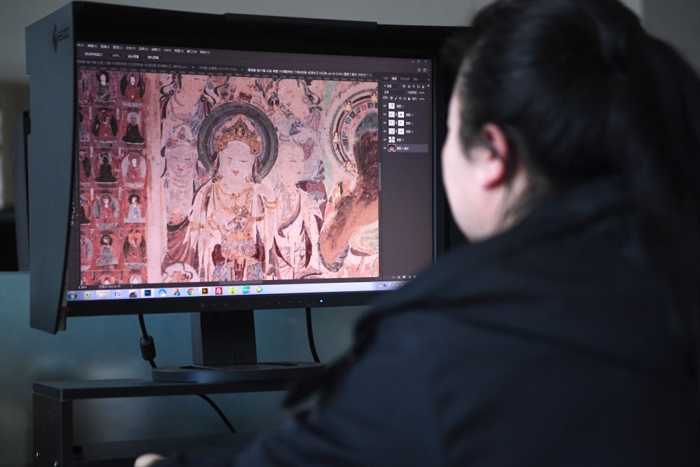 敦煌研究院文物數(shù)字化保護(hù)團(tuán)隊圖像處理人員年海麗在拼接壁畫圖像（2023年4月25日攝）。數(shù)字化探索為莫高窟的保護(hù)與傳承開辟了全新路徑，數(shù)字技術(shù)讓敦煌文物走出洞窟，跨出國門，走向“永久保存、永續(xù)利用”。新華社記者 陳斌 攝