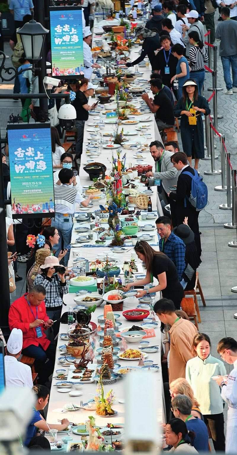 市民和游客在寧波舉辦的第三屆中國(guó)—中東歐國(guó)家博覽會(huì)暨國(guó)際消費(fèi)品博覽會(huì)上品嘗融合中國(guó)和中東歐美食的長(zhǎng)桌宴（2023年5月15日攝）。黃宗治攝/本刊