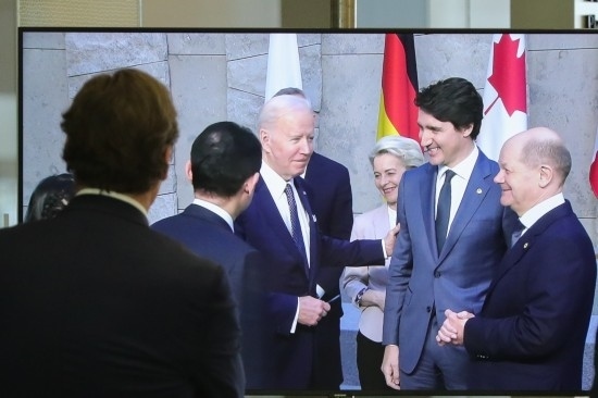 2022年3月24日，在比利時(shí)布魯塞爾的北約總部，一名男子觀看屏幕上美國(guó)總統(tǒng)拜登（右四）、歐盟委員會(huì)主席馮德萊恩（右三）、加拿大總理特魯多（右二）、德國(guó)總理朔爾茨（右一）出席七國(guó)集團(tuán)峰會(huì)合影儀式的畫(huà)面。新華社記者鄭煥松攝