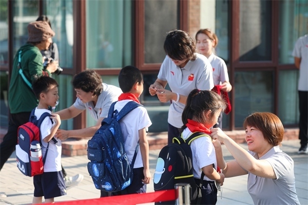 8月30日，雄安史家胡同小學學生體驗學校生活。老師為學生佩戴校徽。