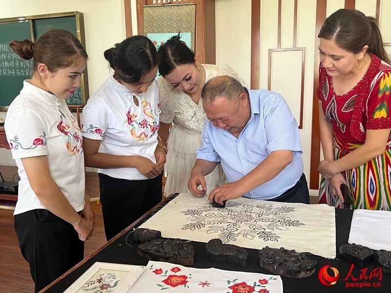 國(guó)家級(jí)非物質(zhì)文化遺產(chǎn)模戳印花布技藝傳承人吾吉阿西木?吾舒爾展示模戳印花布的制作過(guò)程。人民網(wǎng)記者 常雪梅攝