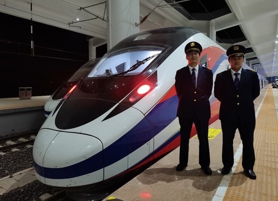 劉銀能（右一）與中國(guó)師父鄔俊鴻在動(dòng)車(chē)組前合影。受訪者供圖