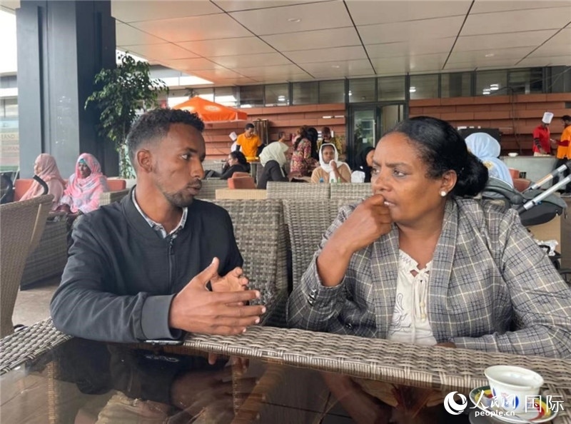 約漢斯（圖左）與德貝拉在友誼廣場(chǎng)咖啡廳交談。人民網(wǎng)記者 趙艷紅攝