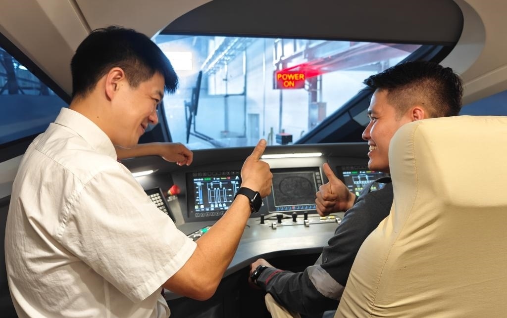 8月25日，在印度尼西亞萬隆的雅萬高鐵德卡魯爾動車所內，中國師傅穆振（左）在向印尼火車司機塞蒂亞萬講解動車組出庫前的上電作業(yè)。