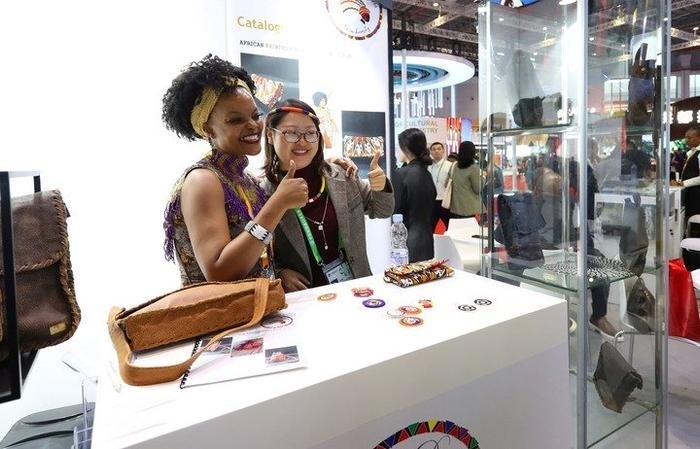 11月6日，一位參觀者（右）在第六屆進(jìn)博會(huì)國(guó)家展南非展臺(tái)試戴傳統(tǒng)首飾。