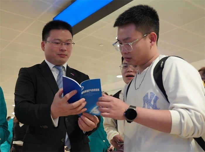 工作人員（左一）在發(fā)放《中國領(lǐng)事保護(hù)與協(xié)助指南》。 中國駐迪拜總領(lǐng)事館供圖