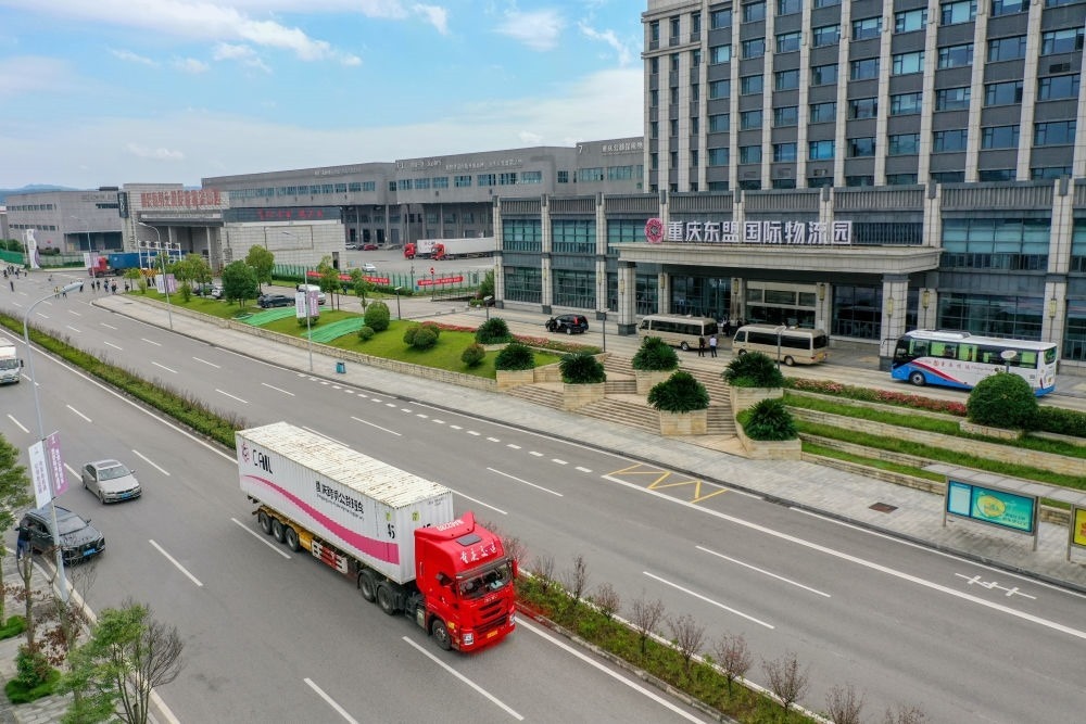 2023年10月11日，滿載筆記本電腦配件、發(fā)電機(jī)組件等產(chǎn)品的西部陸海新通道跨境公路班車從重慶南彭公路保稅物流中心駛出，將途經(jīng)廣西憑祥，直達(dá)越南（無人機(jī)照片）。新華社記者 黃偉 攝