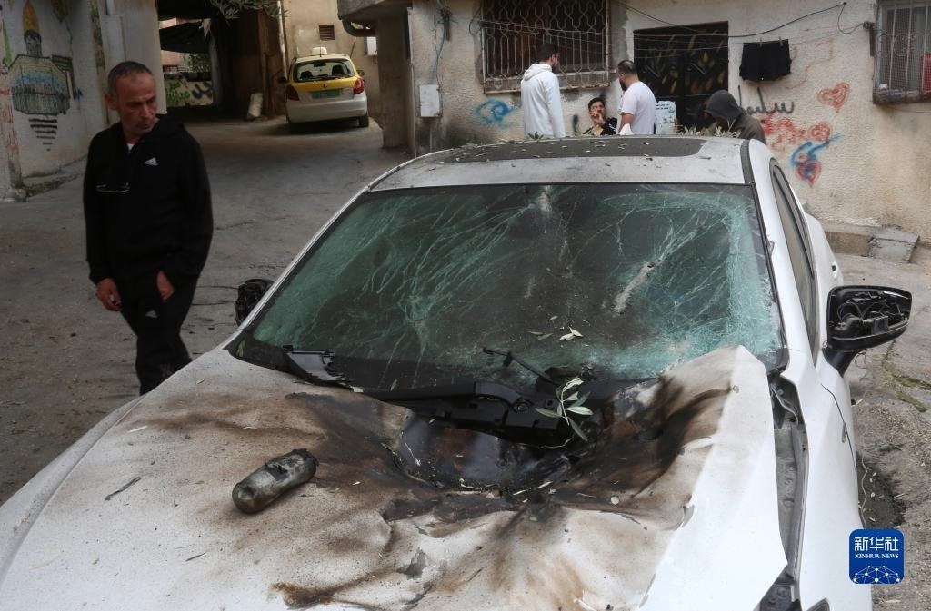 12月17日，在約旦河西岸城市圖勒凱爾姆附近的一處難民營，人們查看在沖突中損毀的車輛。新華社發(fā)（尼達(dá)爾·艾仕塔耶?dāng)z）