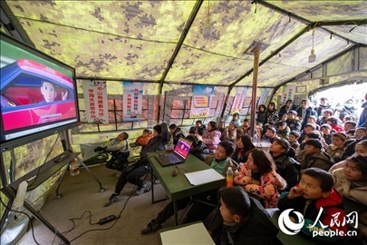 12月22日，在積石山縣大河家鎮(zhèn)大河村安置點，陸軍76集團(tuán)軍某旅搭建的“臨時學(xué)?！眱?nèi)，小朋友正在看動畫片。人民網(wǎng)記者 翁奇羽攝