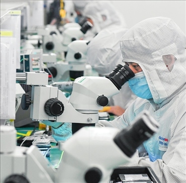 在位于武漢中國光谷的光電器件研發(fā)制造商——武漢光迅科技股份有限公司生產(chǎn)車間內(nèi)，技術(shù)人員在光模塊生產(chǎn)線作業(yè)（2023年4月11日攝）。程敏攝/本刊