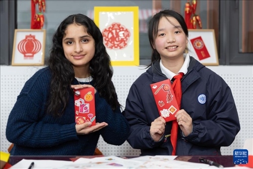 1月28日，美國(guó)馬斯卡廷中學(xué)學(xué)生（左）和復(fù)旦大學(xué)第二附屬學(xué)校學(xué)生展示互相送出的寫有寄語(yǔ)祝福的紅包。 新華社記者 王翔 攝