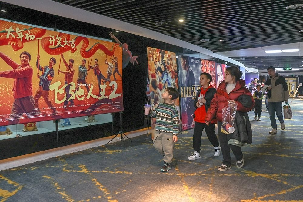 △ 2024年2月16日，在江西贛州一家電影院，觀眾從春節(jié)檔電影的宣傳展板前走過(guò)。