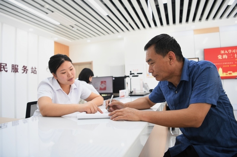 2023年5月23日，河北雄安新區(qū)容東片區(qū)南文營(yíng)社區(qū)居民（右）在社區(qū)便民服務(wù)站辦理業(yè)務(wù)。