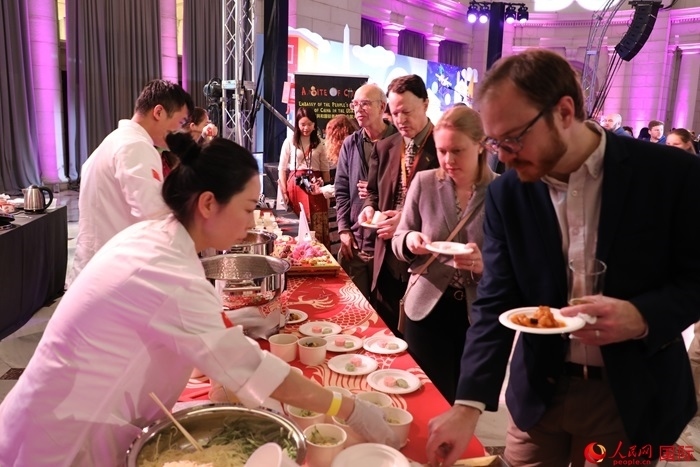 當?shù)貢r間3月7日晚，華盛頓聯(lián)合車站廣場舉行駐美使團“使館主廚挑戰(zhàn)賽”。圖為當?shù)孛癖娫谥袊古_前體驗中國美食。人民網(wǎng)記者 李志偉攝