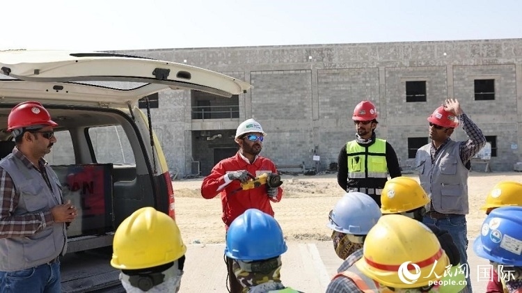 穆薩瓦爾(圖中紅衣人）現(xiàn)場(chǎng)演示工具操作規(guī)范。人民網(wǎng)記者 管克江攝