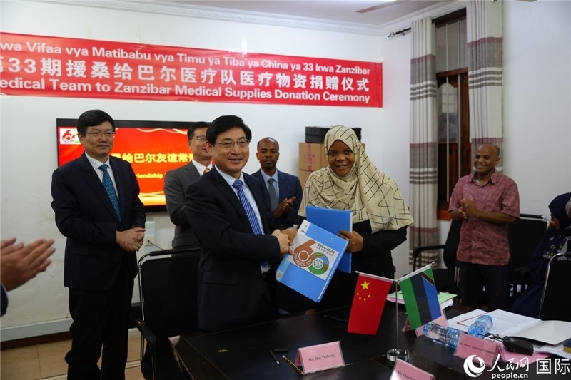 江蘇省蘇北人民醫(yī)院黨委書記束余聲與桑衛(wèi)生部首席秘書哈比巴交換捐贈書。中國援桑醫(yī)療隊供圖