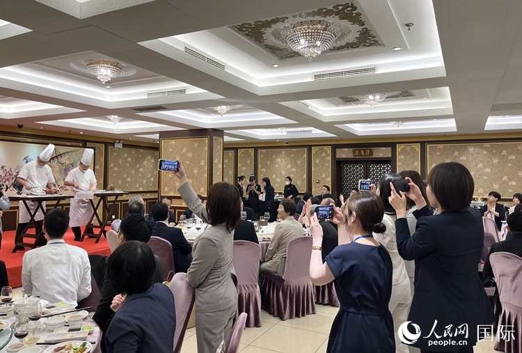 國家級(jí)非物質(zhì)文化遺產(chǎn)、全聚德片鴨工藝吸引代表團(tuán)成員拍照留念。