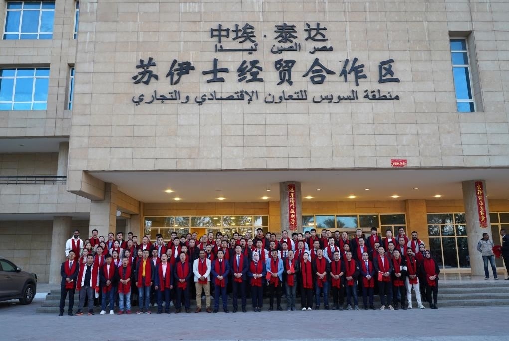 2024年2月11日，在位于埃及蘇伊士省的中?！ぬ┻_(dá)蘇伊士經(jīng)貿(mào)合作區(qū)，中埃員工在合作區(qū)辦公大樓前合影拜年。新華社發(fā)（泰達(dá)合作區(qū)供圖）