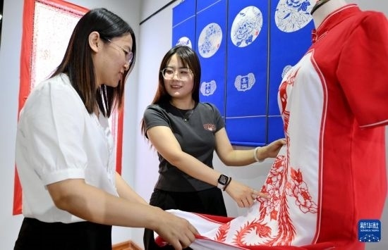 5月31日，在衡水市阜城縣一家剪紙工作室，游客在觀賞帶有剪紙?jiān)氐钠炫邸? width=