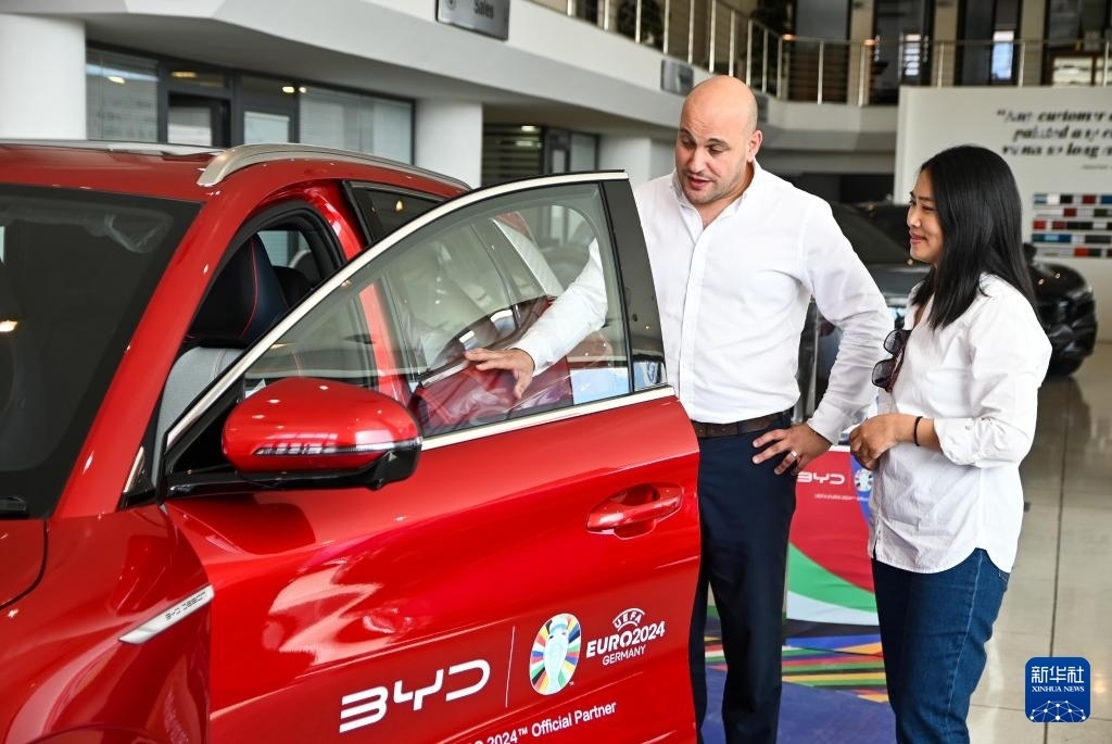2024年5月29日，在馬耳他比爾基卡拉，馬耳他哈桑-扎米特汽車公司首席執(zhí)行官德古阿拉（左）介紹一輛比亞迪純電動汽車。新華社發(fā)（喬納森·博格 攝）