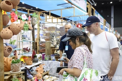 游客在蘭納博覽會特色展位上選購工藝品。人民網(wǎng)記者楊一攝