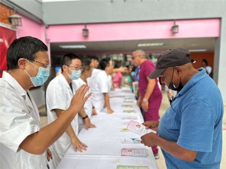 援圭醫(yī)療隊隊員們在啟動儀式上為當?shù)孛癖姺职l(fā)宣傳手冊。中國援助圭亞那醫(yī)療隊供圖