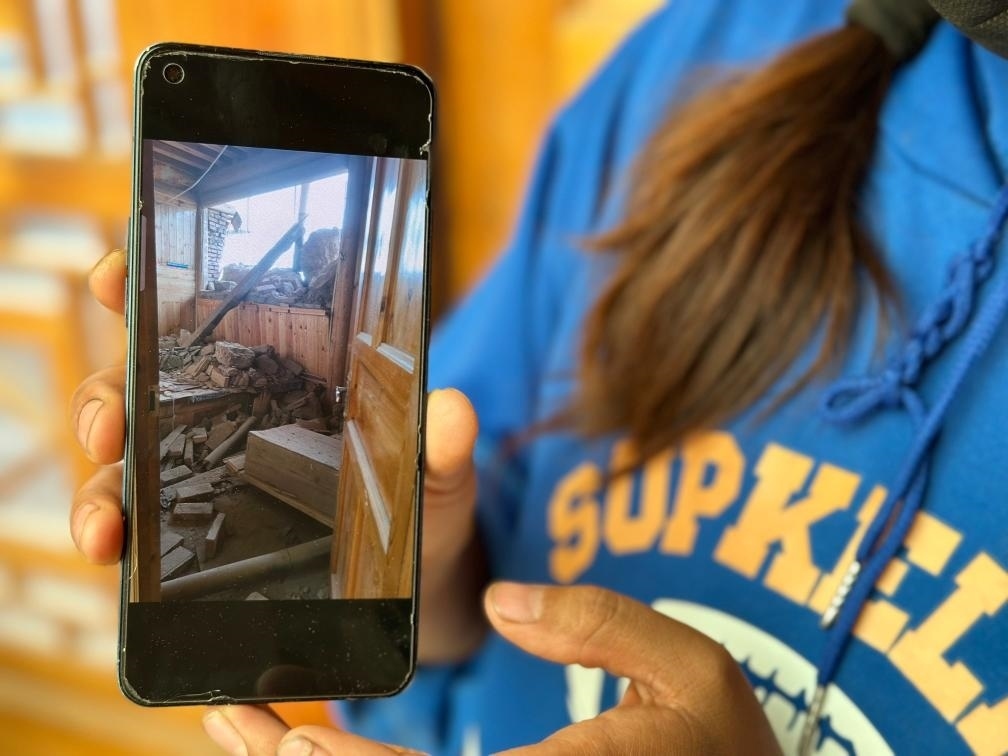 圖為7月17日拉毛東智在手機(jī)上找出地震后房屋受損的照片。新華社記者 張子琪 攝