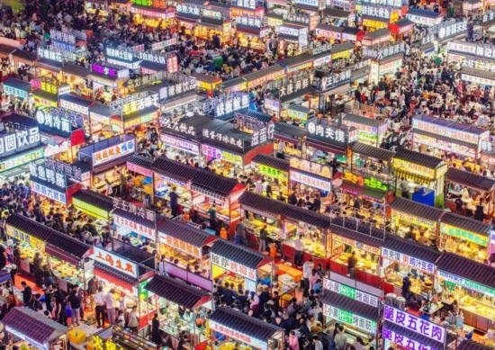 2024年4月21日，人們?cè)诤颖笔≌h小商品夜市品嘗美食（無(wú)人機(jī)照片）。新華社發(fā)（武志偉 攝）