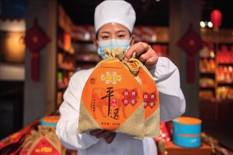 在位于山西省晉中市平遙縣的平遙古城南大街的一家平遙牛肉店內(nèi)，工作人員展示一款牛肉產(chǎn)品（資料照片）楊晨光攝 / 本刊