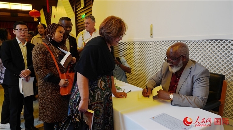 譚哲理在活動現場簽名贈書。人民網 劉暢攝