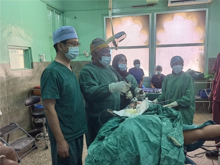 隊長蔣國慶（左一）關注當?shù)蒯t(yī)生手術情況。中國援桑醫(yī)療隊供圖