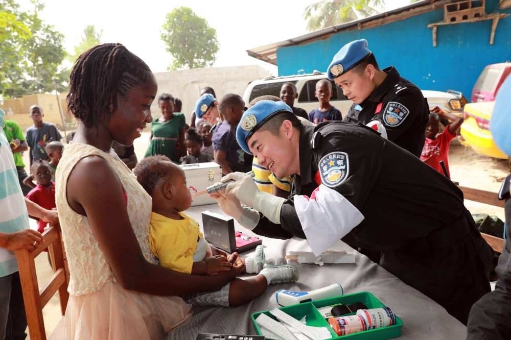 2017年12月28日，在利比里亞蒙羅維亞，中國維和警察防暴隊醫(yī)療人員為兒童做口腔檢查。