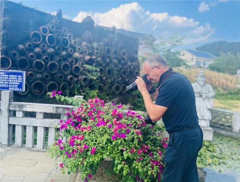 遠(yuǎn)處黔北民居錯落有致，近處一只黑色的蝴蝶穿梭于粉紫色三角梅花叢間隙，與俄羅斯“大歐亞”總編輯弗拉基米爾·別列日內(nèi)赫的鏡頭玩起了捉迷藏，“你追我逃，不亦樂乎”。（張亞欣攝）