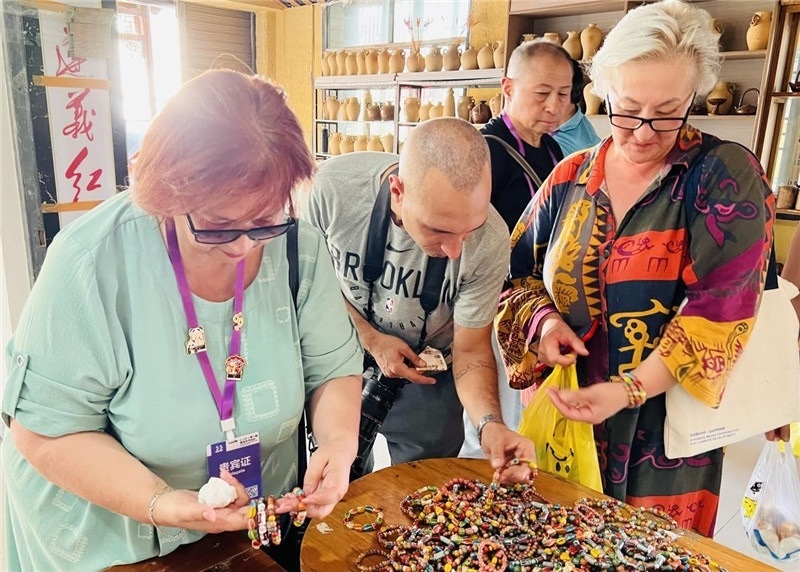 歐亞媒體考察團(tuán)成員在母氏陶藝館內(nèi)挑花了眼，色彩絢麗、質(zhì)地均勻的陶藝手串讓他們愛不釋手。“這里的東西都太實(shí)惠了！”塔吉克斯坦《索格特真理報(bào)》政論部主任娜塔利婭·多羅費(fèi)耶娃說。花茂村的特色產(chǎn)品物美價(jià)廉，讓考察團(tuán)成員為家人好友買到了心儀的禮物，也為此次以四川成都為起點(diǎn)，路經(jīng)南充、廣安至貴州遵義的考察行程畫上了圓滿句號。（張亞欣攝）