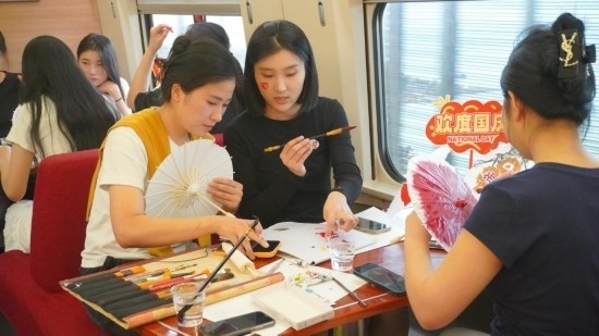 10月1日，旅客們?cè)贕1634次列車上給油紙傘作畫。新華社記者周義 攝