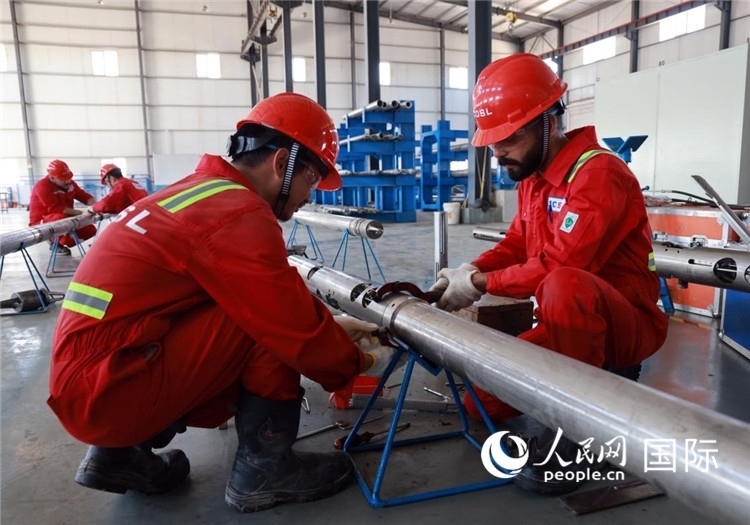 中伊員工共同在檢修鉆井設(shè)備。人民網(wǎng)記者管克江攝