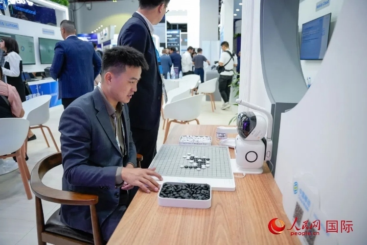 觀眾在中國移動國際有限公司展臺體驗智慧圍棋機器人。人民網 塔里克·易卜拉欣攝