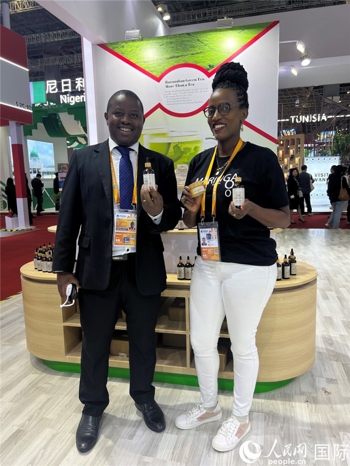 6月6日，布隆迪駐華大使館一等參贊布利馬索·阿爾弗雷德 (左，Bulimaso Alfred) 和參展商卡馬里扎·埃斯特拉 (Kamariza Estella) 在第七屆中國國際進口博覽會布隆迪館展示當地生產的辣木油。（人民網 艾里士 攝）