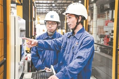 在廣西柳工機(jī)械股份有限公司生產(chǎn)車間內(nèi)，一名高級(jí)技師（右）給徒弟講解數(shù)控設(shè)備操作細(xì)節(jié)。新華社記者 曹祎銘攝