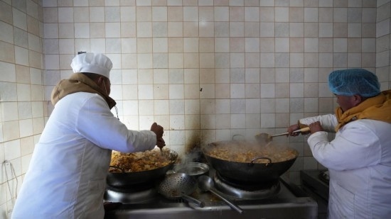 1月14日，服務(wù)隊(duì)的兩名廚師正在為村民們做午飯。新華社記者 邱星翔 攝