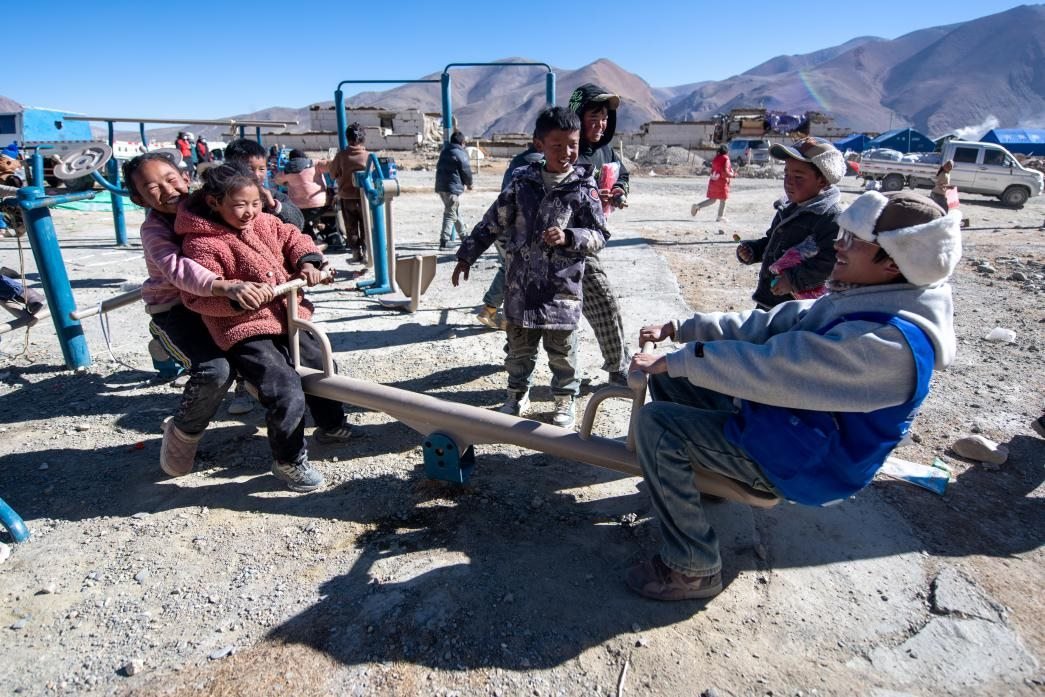 1月11日，在定日縣措果鄉(xiāng)塘仁村安置點，西藏星光社會工作服務中心志愿者和孩子們一起玩耍，進行災后心理疏導。人民網(wǎng)記者 翁奇羽攝
