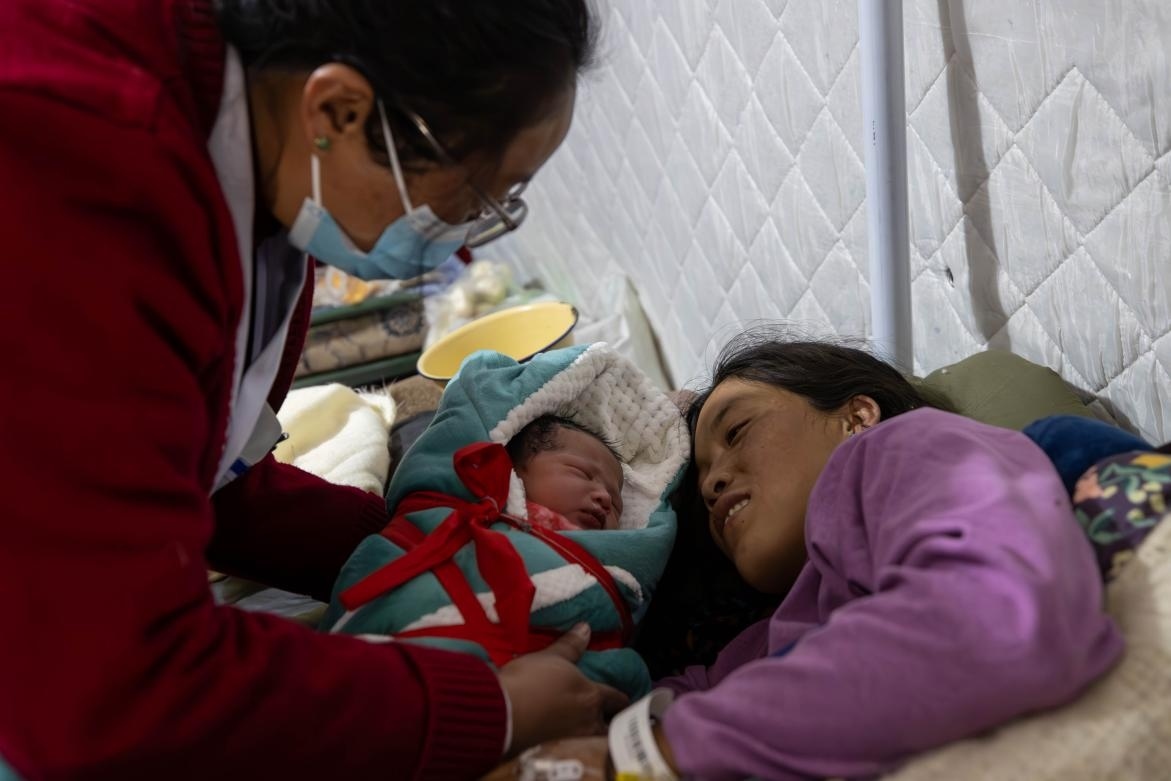 1月10日，定日縣中心醫(yī)院的婦產科醫(yī)生悉心照看一位母親和她懷里的新生兒。人民日報記者張武軍攝