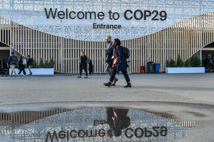 2024年11月15日，在阿塞拜疆首都巴庫(kù)，人們經(jīng)過(guò)聯(lián)合國(guó)氣候變化巴庫(kù)大會(huì)的會(huì)場(chǎng)。新華社記者 曹陽(yáng) 攝